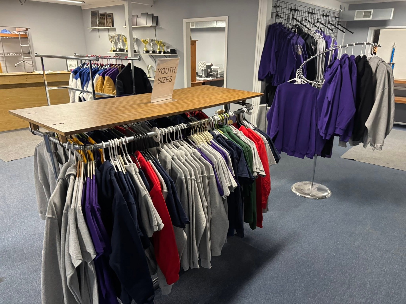 Inside New Haven Trophies & Shirts — trophies on the shelf and racks of school spirit wear